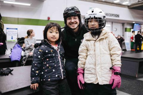 skating volunteer helping two children