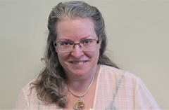 A photo of a woman with glasses searing a white shirt similing