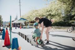 Child riding bike over ramp with recreation leader supervising