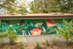 Person standing in front of floral art mural on building at Lions Park