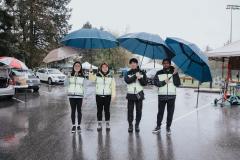 Community police volunteers standing under umbrellas in the rain