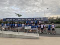 Group of cyclists in front of Terry Fox Hometown Square sign