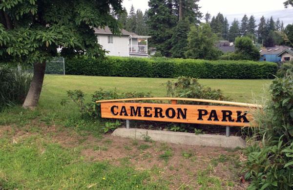 Signage for Cameron Park. The sign is wooden with dark lettering.