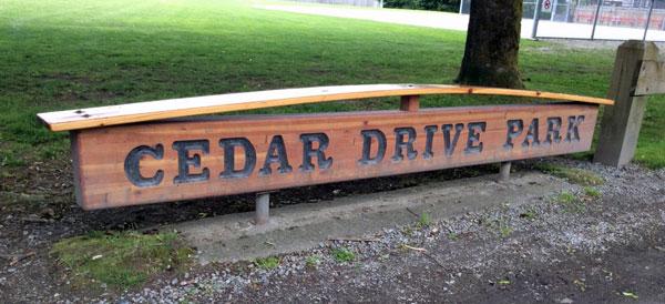 Signage for Cedar Drive Park. The sign is wooden with dark lettering.