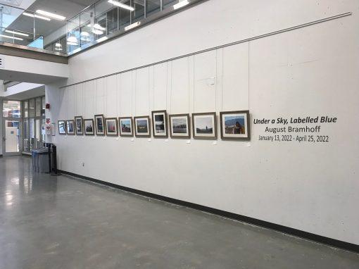 Row of artwork on display. They are hanging from an art gallery's wall.