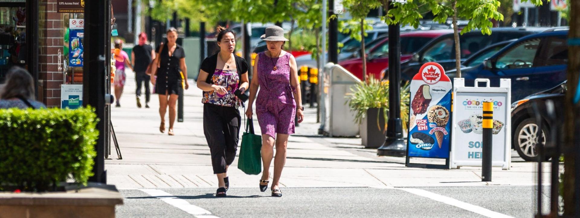 Two women walking down the street together in summer outfits