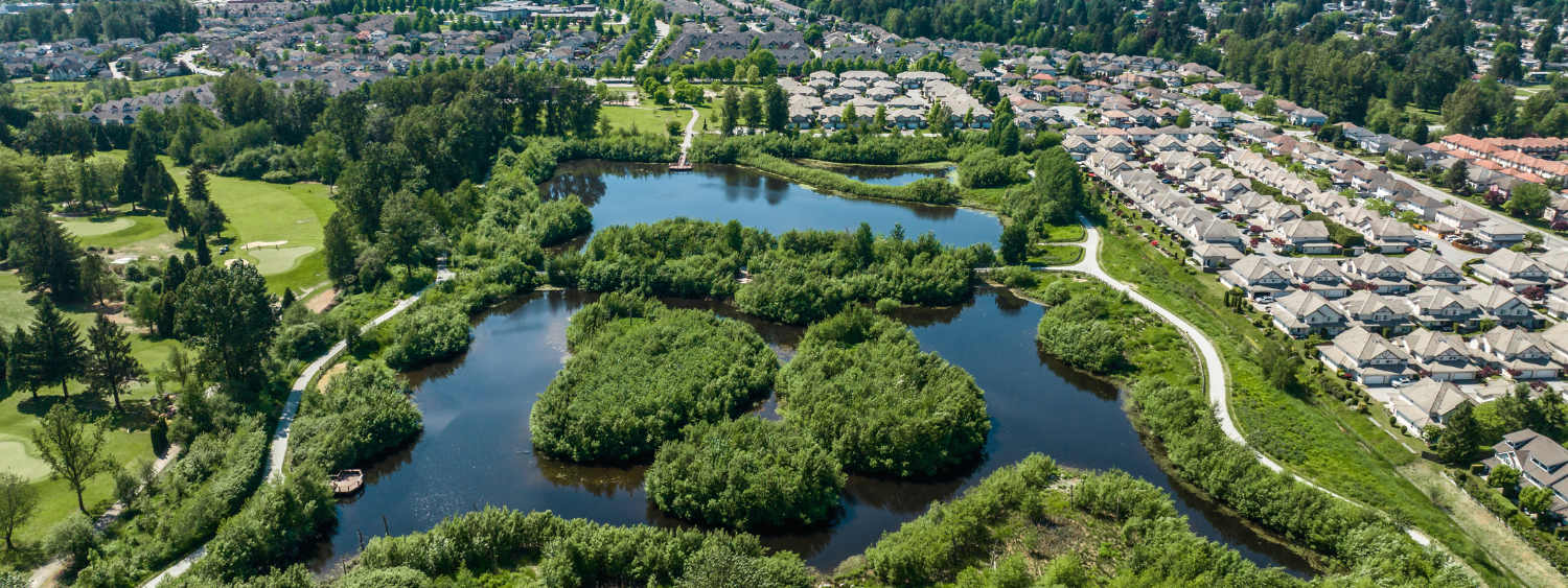 Aerial view of a waterway with houses on he right and a golf course on the left