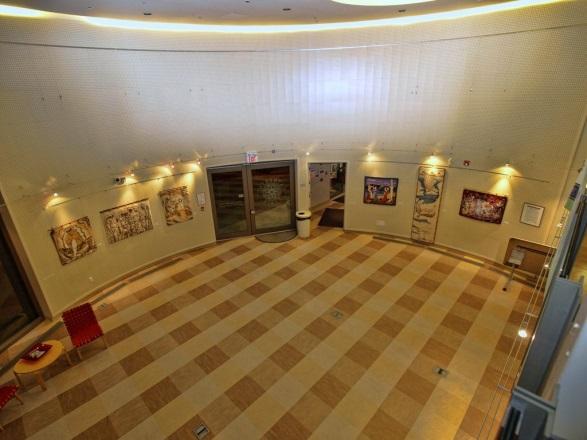 Interior space of art gallery. The gallery has yellowish carpets with very high ceilings.