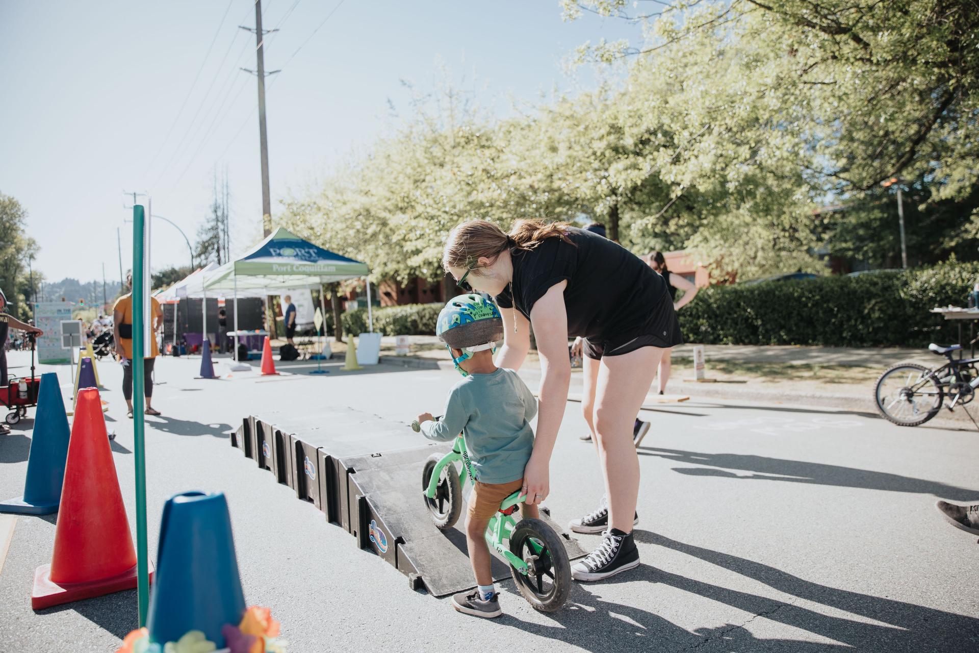 Child riding bike over ramp with recreation leader supervising