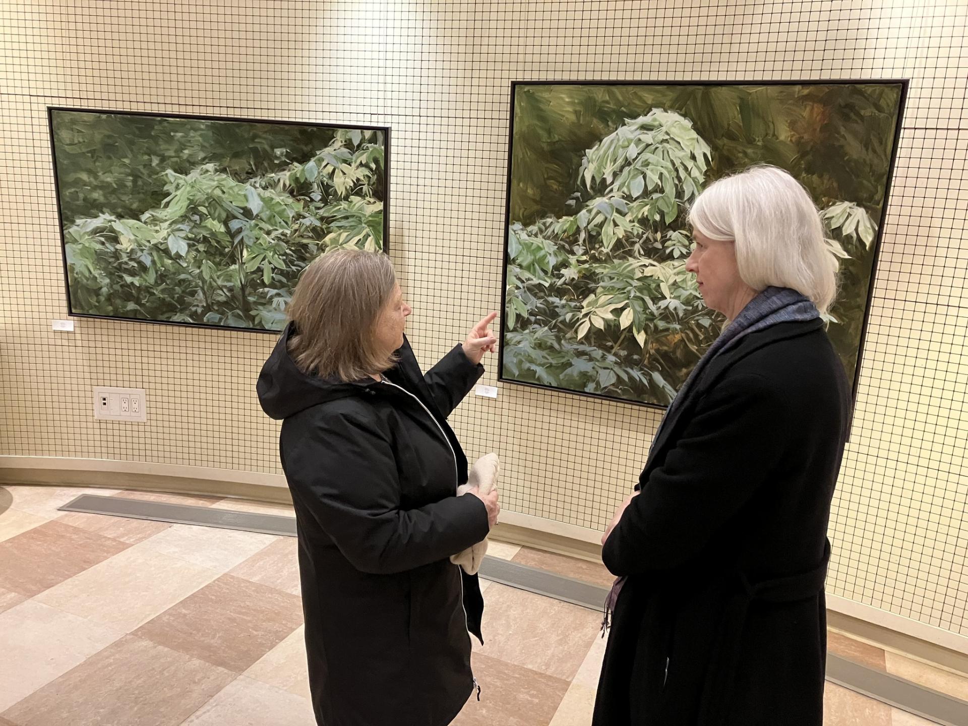 Two people standing in front of two pieces in art gallery