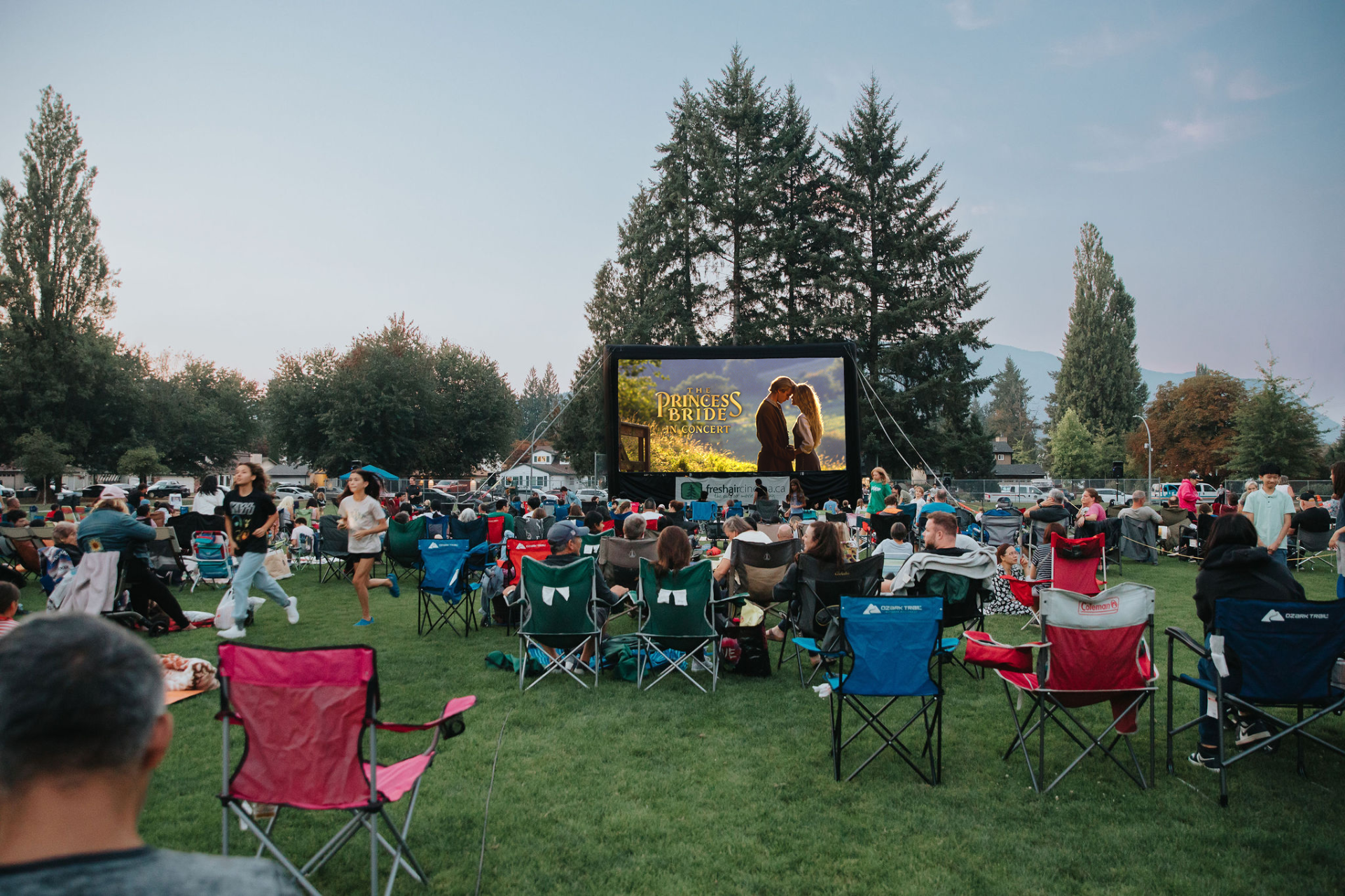 outdoor movie screen in the park with people gathered around