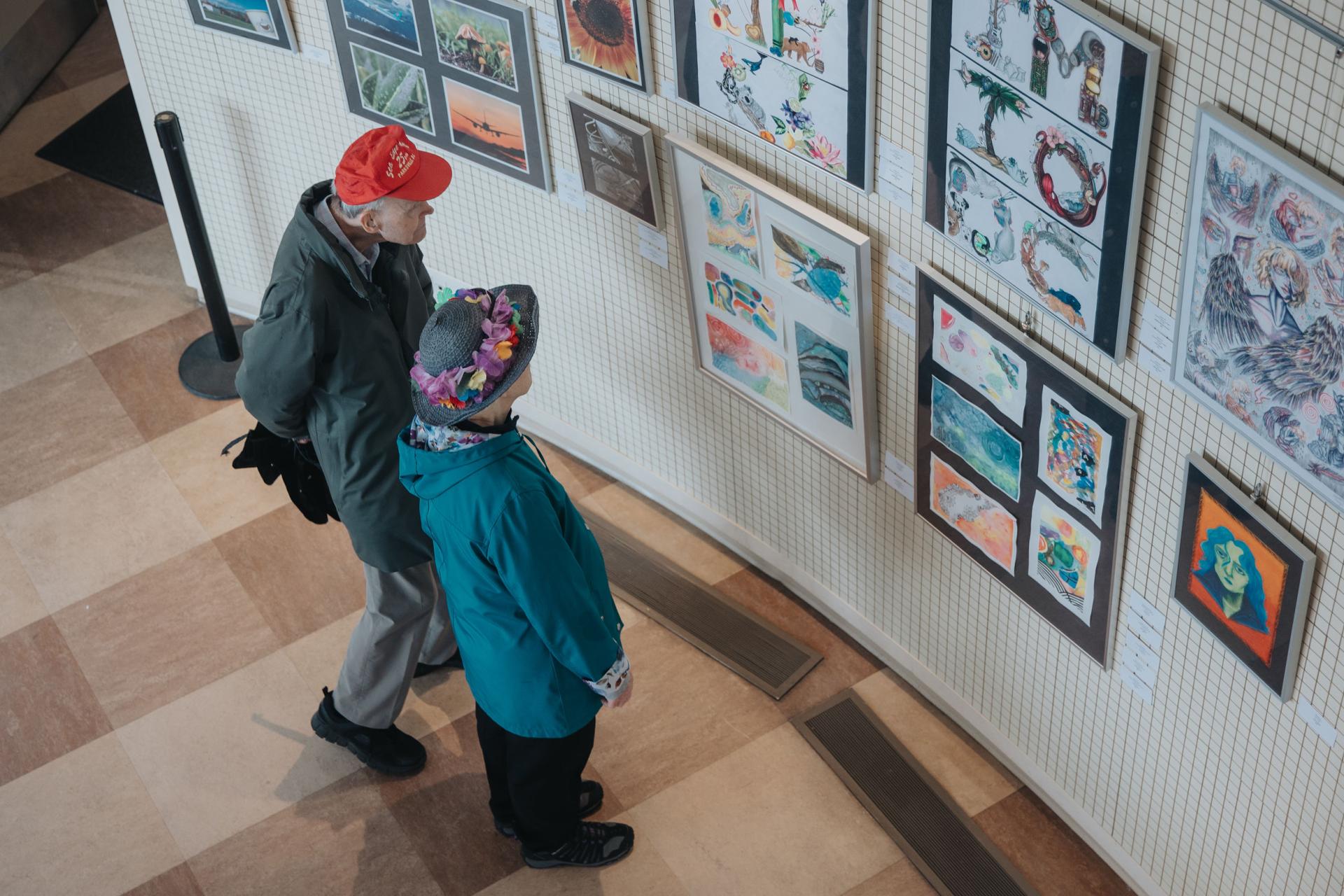 two people in Michael Wright Art Gallery, looking at artwork on display