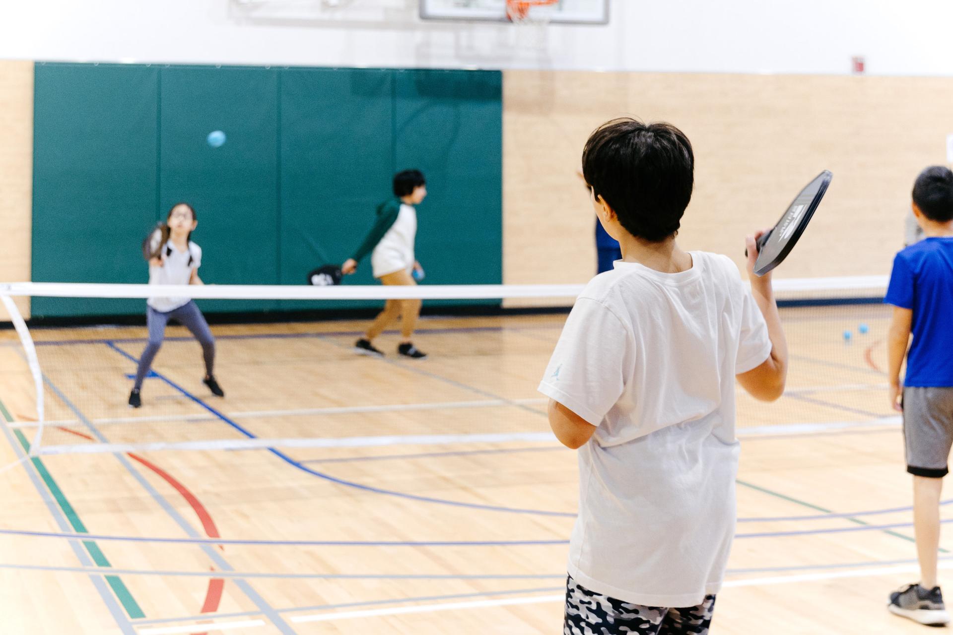 kids playing pickleball in gymnasium